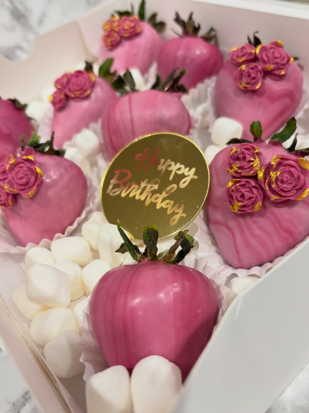 Pink chocolate-covered strawberries with chocolate roses and a gold Happy Birthday topper