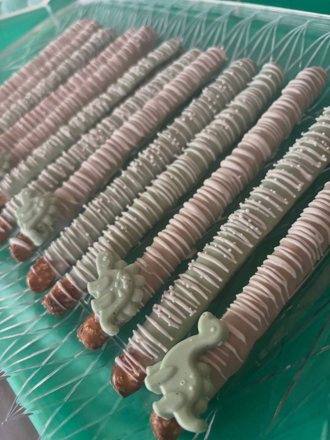 Pink and sage chocolate-dipped pretzel rods on a party table