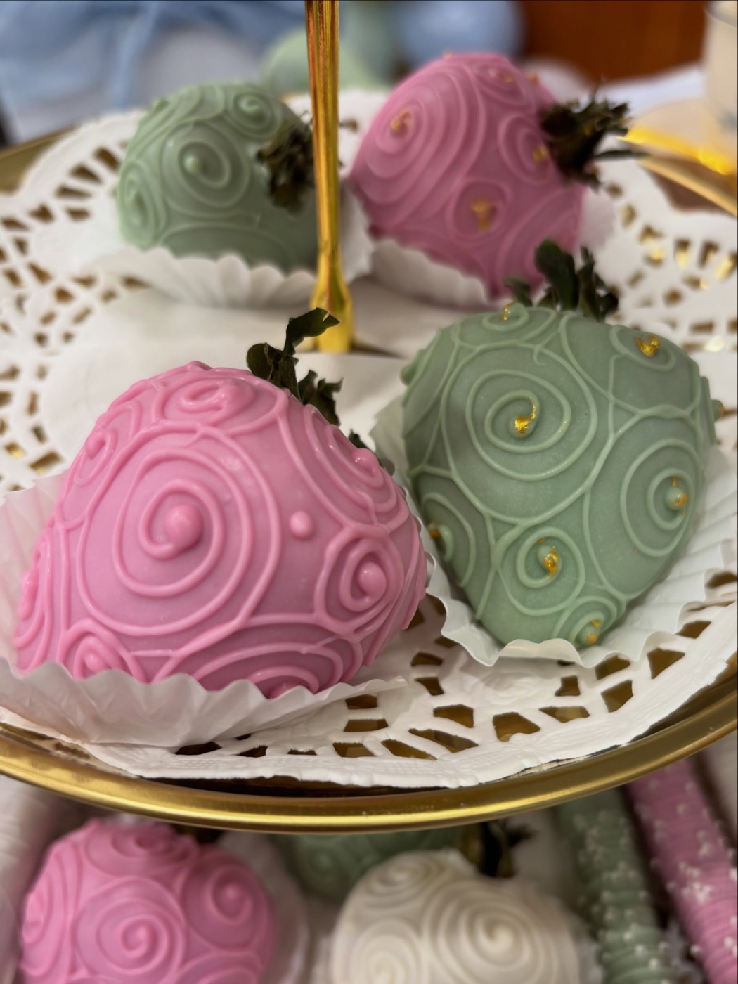 Blush pink and sage strawberries with piped swirls on a gold stand